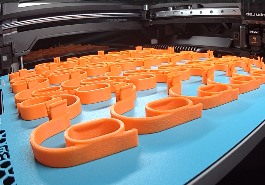 Kleinserien Produktion Orange 3D-gedruckte Formen liegen auf einer blauen Druckplatte.