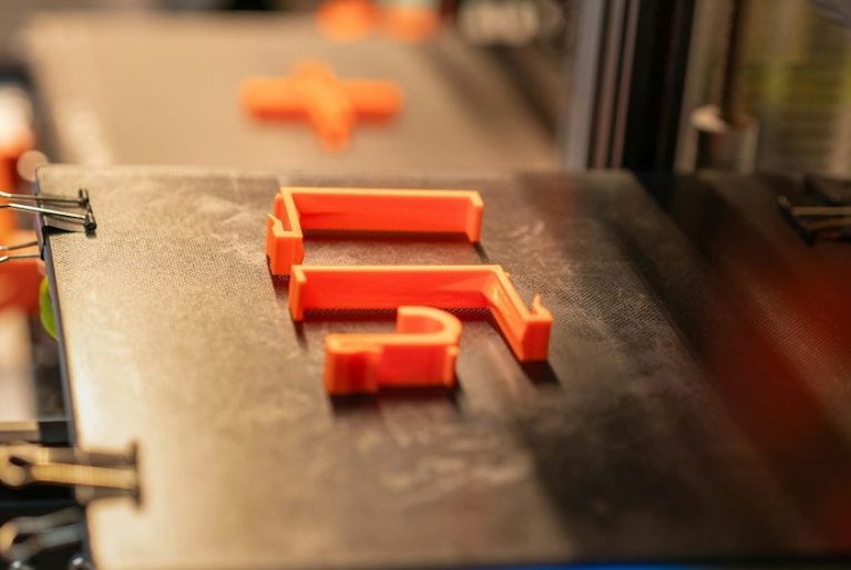 Rote 3D-gedruckte PLA Teile auf einer Druckplattform.