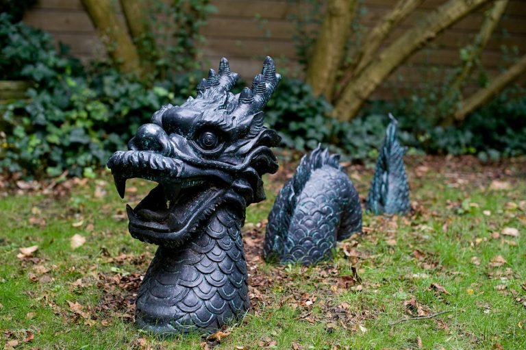 Schwarze Drachenfigur mit detailliertem Kopf und geschwungenem Körper im Garten