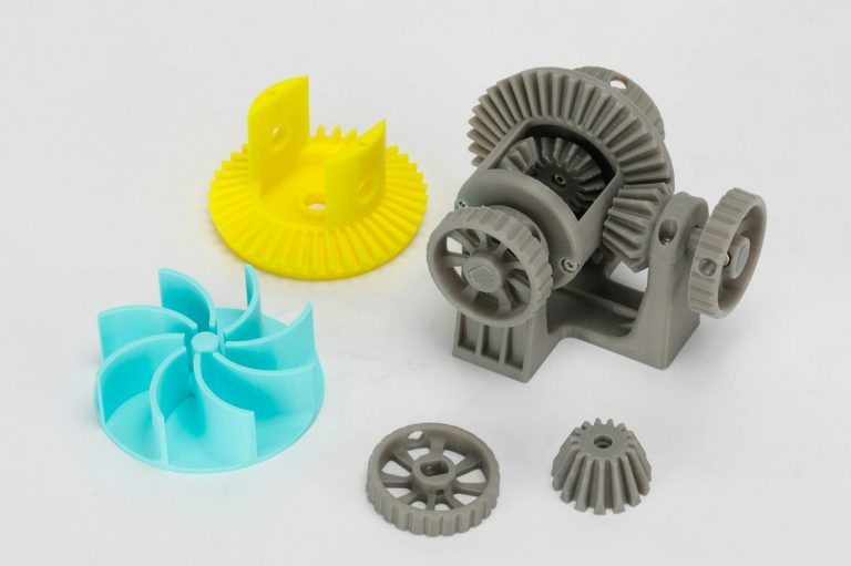 Graue und farbige mechanische Zahnräder und Bauteile auf weißem Hintergrund.